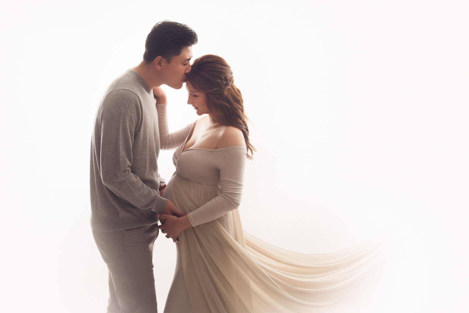 loving husband kissing his wife forehead during their maternity photography session