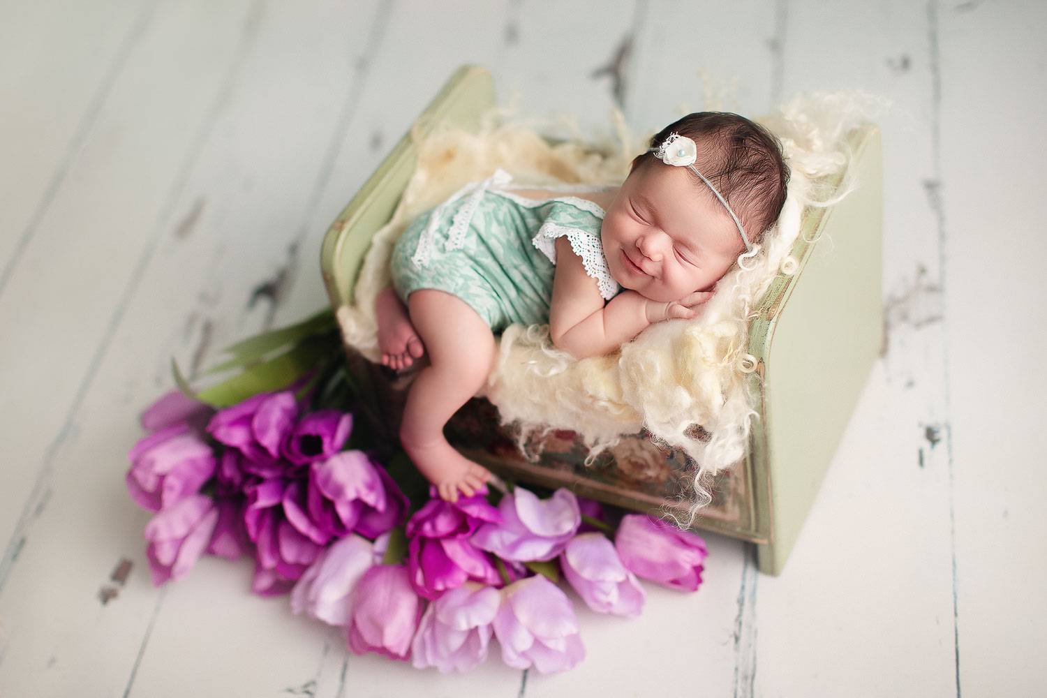 newborn baby girl with a green outfit smile | Jana photography