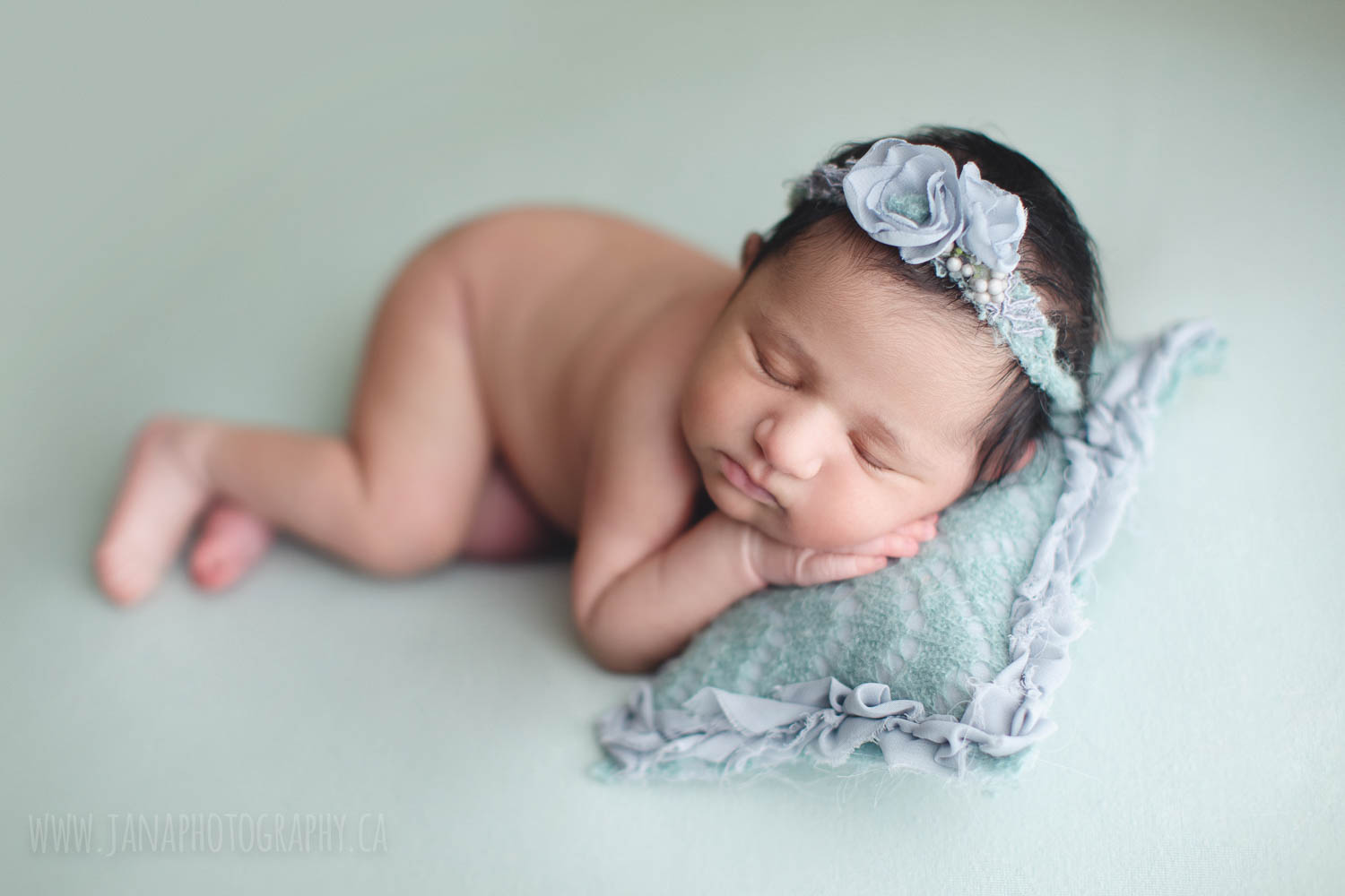 newborn photography baby girl a green setup and pillow