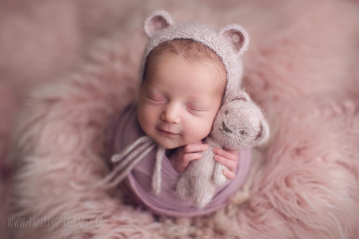 baby girl smiling in a pink background - holding a bear