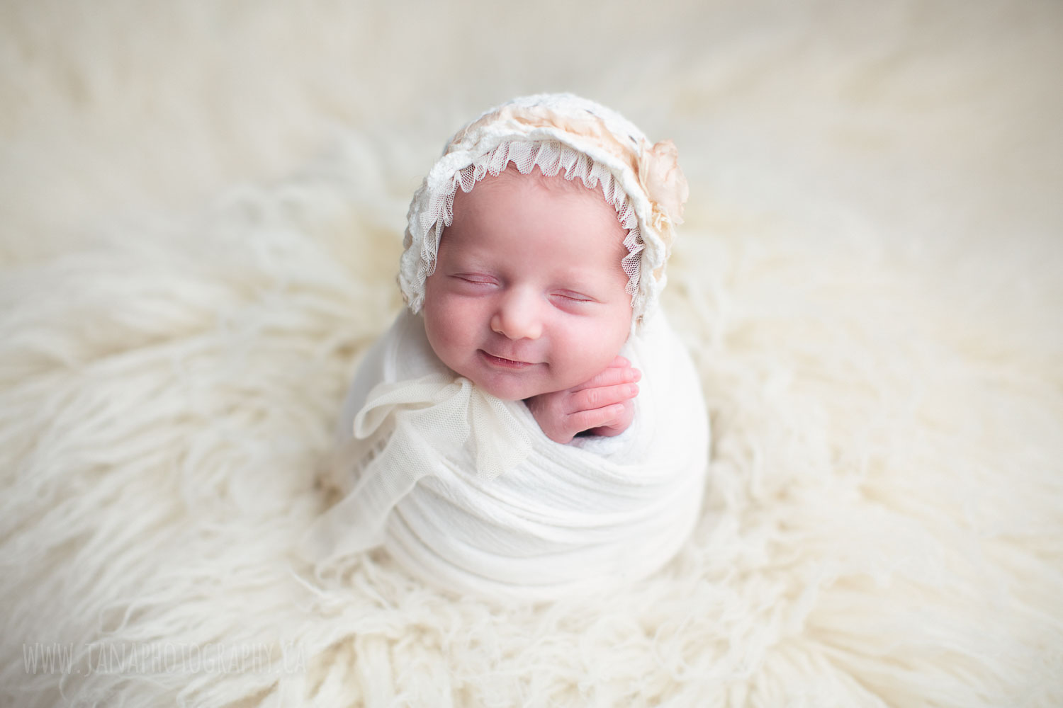 newborn baby girl in a white setup fur smiling - jana photography