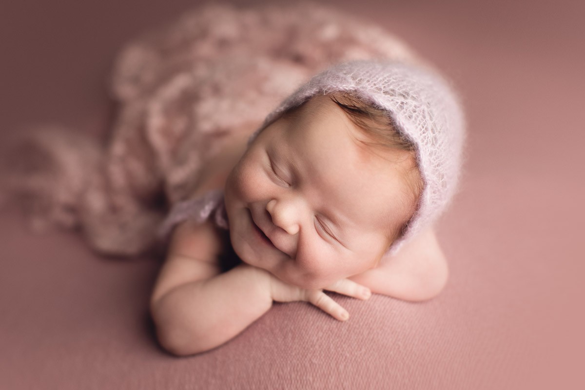 newborn photography baby girl in pink setup smiling