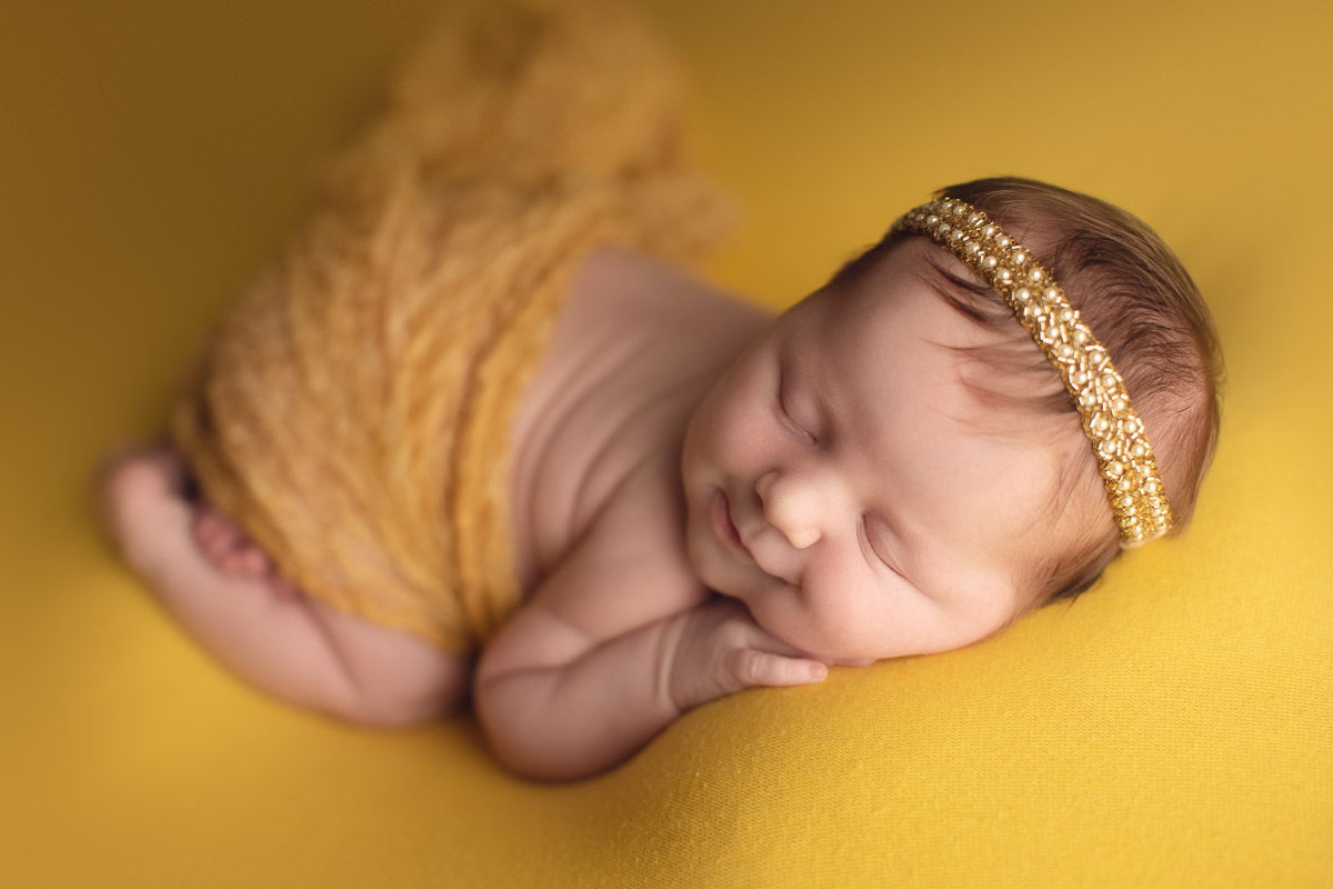 newborn baby girl - smile - yellow background