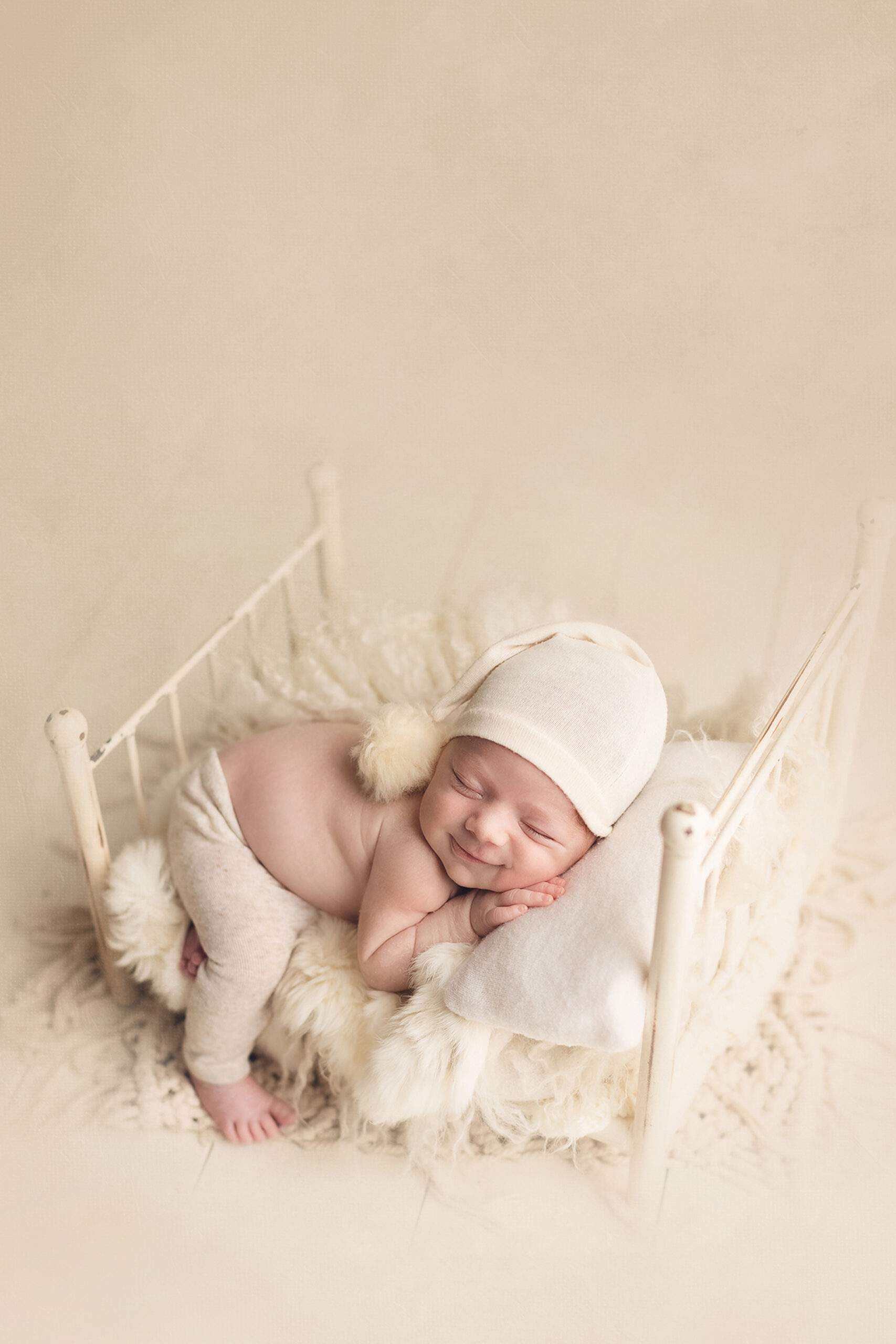 Newborn photography baby boy sleeping in a white bed