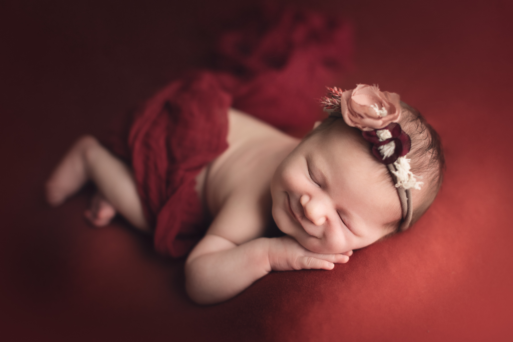 newborn photography classic package sample - baby girl smiling in a red background fabric